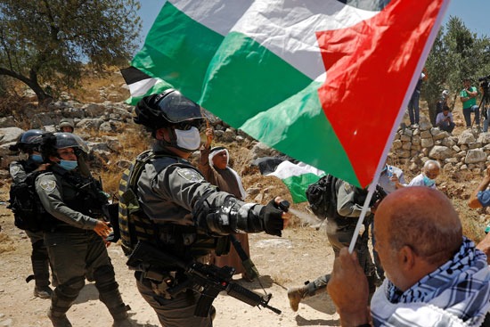 فلسطينى يحمل علم بلاده ضد قوات الاحتلال