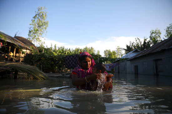 سيدة تحمل طفلها خوفا من الغرق فى مياه الفيضانات