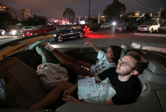 أشخاص يشاهدون فيلمًا أثناء وجودهم في سياراتهم بمنطقة جبيل