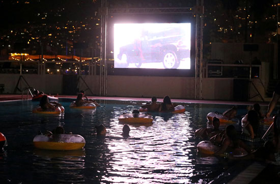 أشخاص يشاهدون فيلمًا أثناء وجودهم في حمام السباحة فى منطقة جوبية