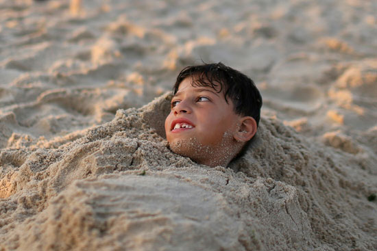 طفل يستمتع برمال الشاطئ