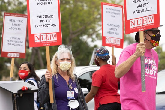 العاملون يحملون لافتات تطالب بتوفر الرعاية الطبية