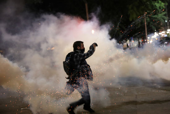متظاهر يلقي علبة غاز مسيل للدموع مرة أخرى تجاه الشرطة