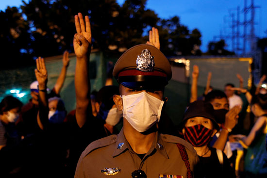ضابط شرطة تايلاندي ومن خلفه المتظاهرين