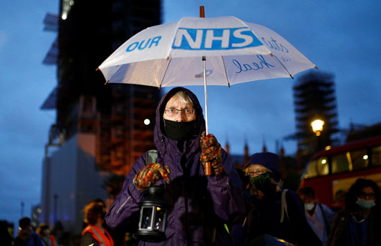 المتظاهرون يحملون شعار الخدمة الطبية الوطنية فى بريطانيا