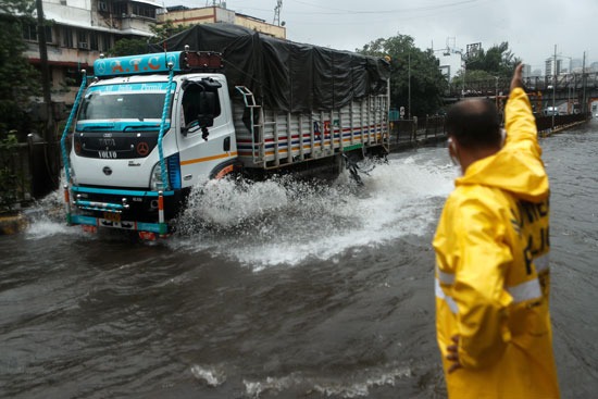 عامل بلدي يوجه حركة المرور على طريق مغمور بالمياه أثناء هطول أمطار غزيرة في مومباي