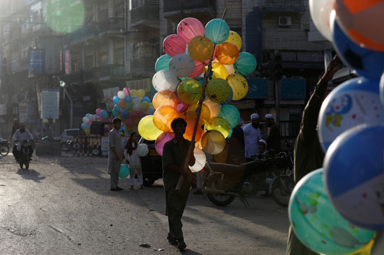 صبي يمشي مع مجموعة من البالونات لجذب الأطفال أثناء بيعه خارج المسجد أثناء الاحتفال بعيد الأضحى ، مع استمرار وباء فيروس التاجي (COVID-19) في كراتشي ،