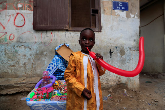 صبي يحاول نفخ بالون اشتراه للتو خلال الاحتفال بيوم عيد الأضحى في داكار