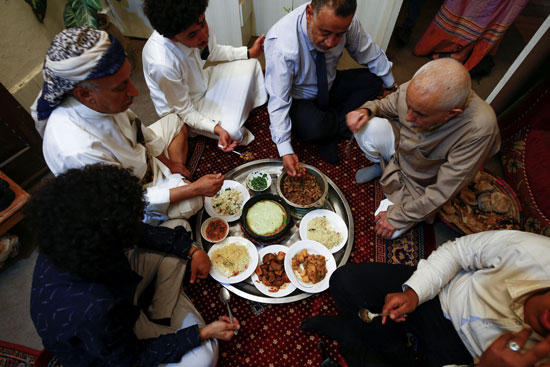 أفراد أسرة يمنية يتناولون الغداء في المنزل خلال عيد الأضحى في صنعاء باليمن