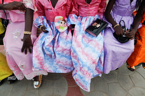 فتيات يحملن حقائبهن يجلسن على مقعد عام خلال الاحتفال بيوم عيد الأضحى في داكار