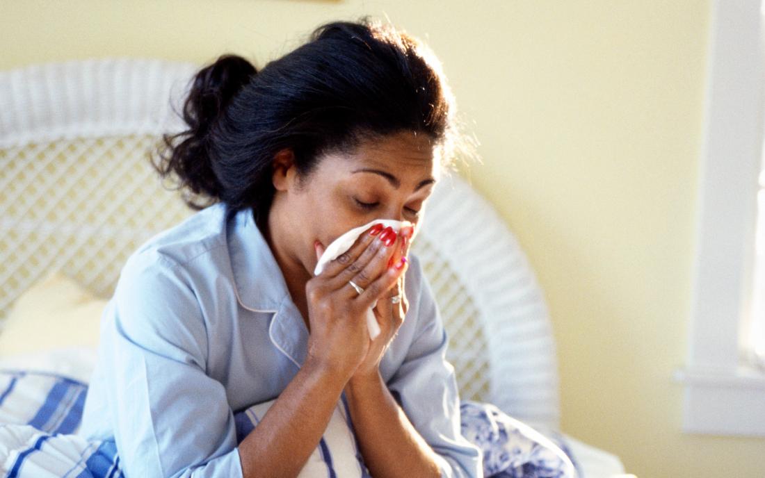 a-woman-sat-in-bed-and-blowing-her-nose-because-she-has-the-flu