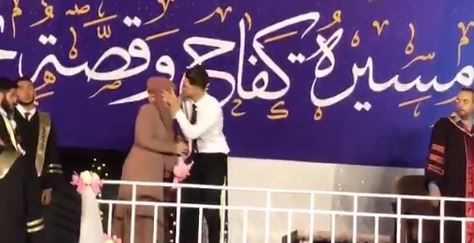 الشاب الفلسطينى يقبل أمه بعد الصعود بها على المنصة