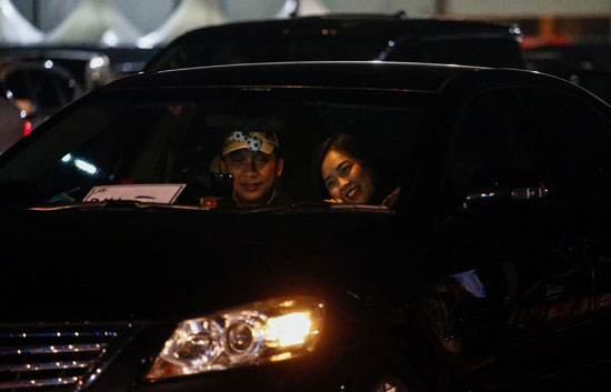 رجل وزوجته يتابعون الحفل من داخل سيارتهم