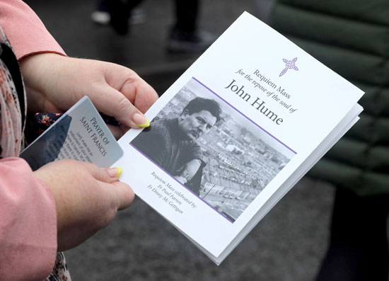 أحد الحاضرين يحمل بطاقة بجنازة جون هيوم بكاتدرائية سانت يوجين