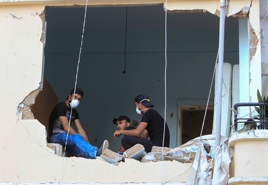 لبنانيون يجلسون في منزلهم الذي دمر بعد انفجار ميناء بيروت