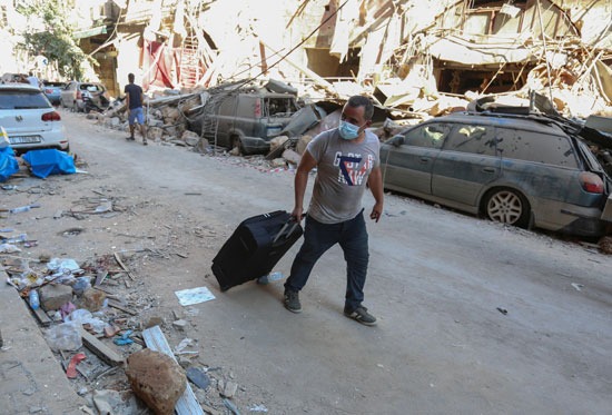 لبناني تاركًا منزله بعد تدميره إثر الانفجار