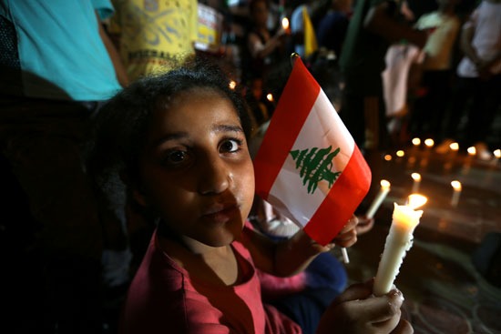 طفلة فلسطينية تحمل شمعة وعلم لبنان