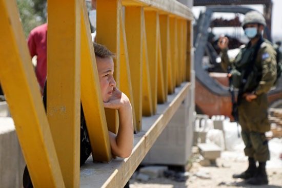 طفل يقف على حاجز قوات الاحتلال