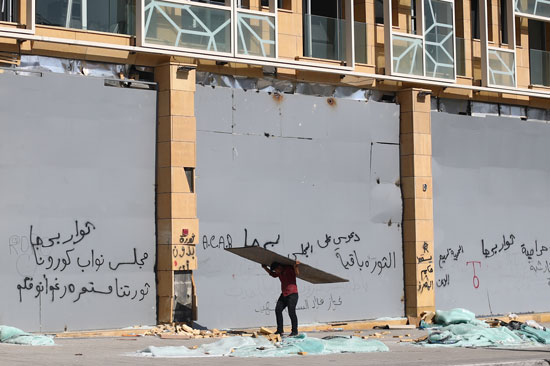 مواطن-يحمل-لوح-خشبي-وفي-الخلفية-عبارات-استهجان-ضد-الحكومة-اللبنانية