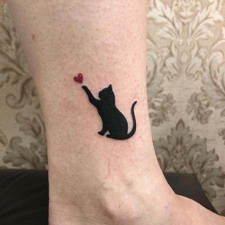 تاتو قطة سوداء وقلب أحمر على الساق