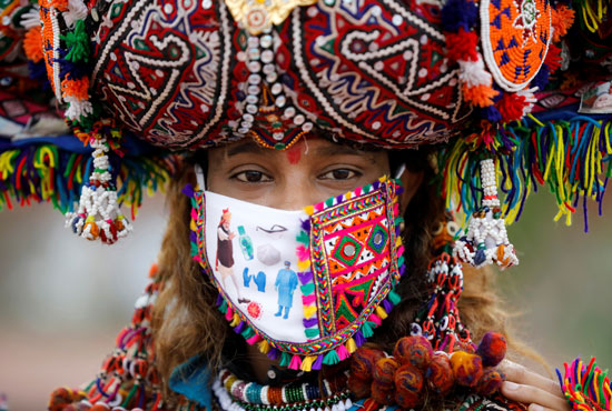 مشارك يرتدي زيًا تقليديًا ويرتدي قناعًا للوجه