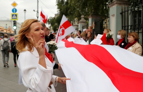 السيدات يحملن علم كبير لبيلاروسيا في التظاهرة