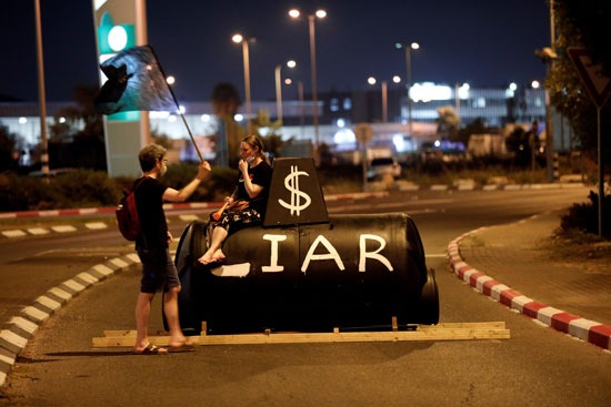 متظاهران بالقرب من مجسم كتب عليه كاذب نسبة إلى نتنياهو