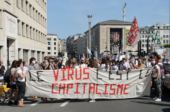 لافتة كتب عليها الرأسمالية هي الفيروس خلال مسيرة نظمها عمال الصحة العامة البلجيكيون (3)