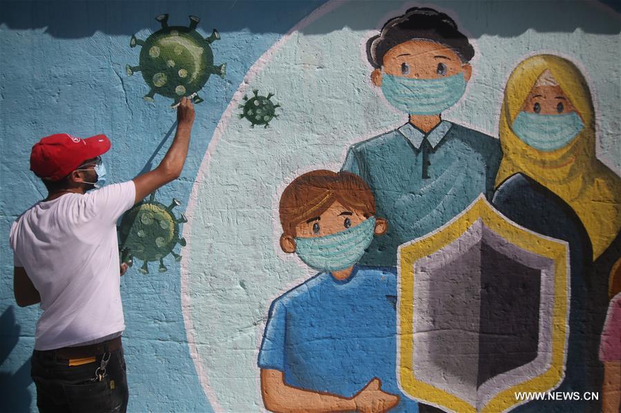 رسام يرسمد جدارية فى غزة حول كورونا