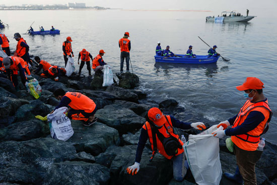 عمال ومتطوعون حكوميون يلتقطون القمامة على طول شاطئ خليج مانيلا