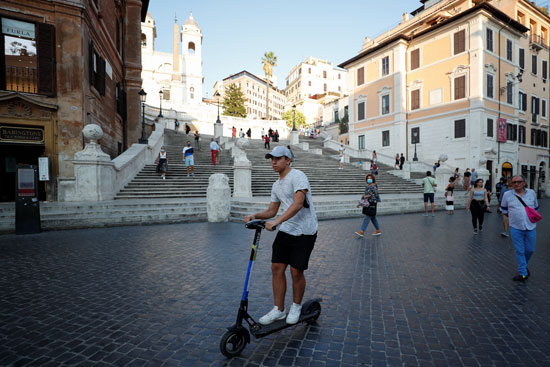 رجل يركب دراجة بخارية كهربائية أمام السلالم الإسبانية في روما