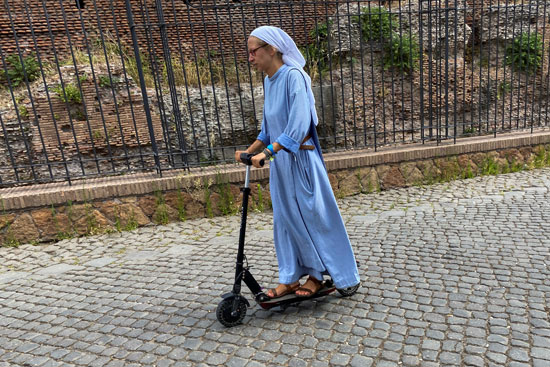 راهبة تركب دراجة بخارية كهربائية بالقرب من الكولوسيوم في روما