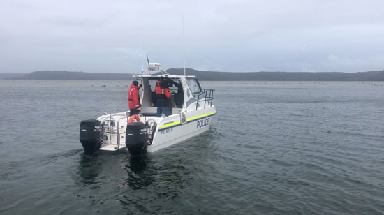  قارب شرطة بجوار أشخاص يساعدون الحيتان العالقة في ماكواري هيدز  (2)