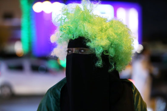 امرأة تحتفل باليوم الوطني السعودي مرتدية باروك بألوان العلم السعودي