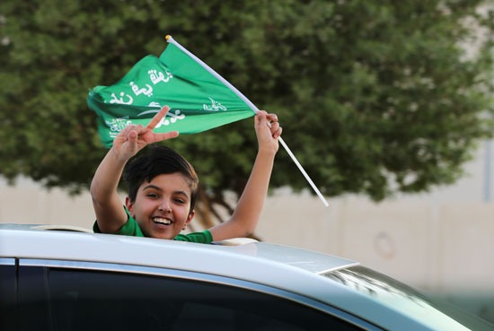 طفل يلوح بعلم السعودية احتفالا باليوم الوطني الـ 90