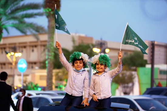 طفلان يحملان العلم السعودي فرحا باليوم الوطني للمملكة