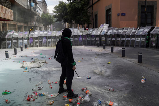متظاهرة مكسيكية تقف أمام جحافل الشرطة