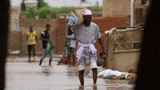 رجل يحمل أغراضه بعد الفيضان