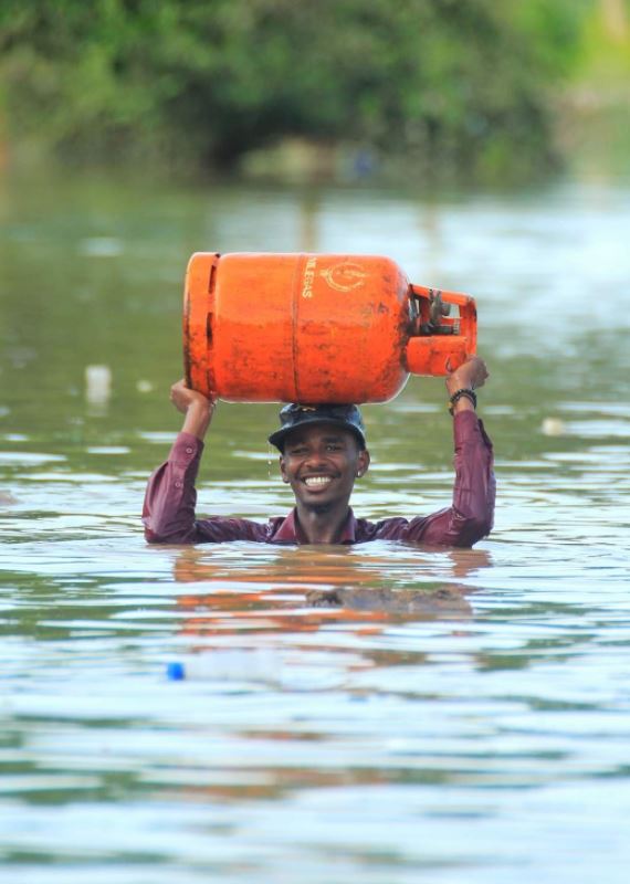 سوداني يحمل أسطوانة غاز وسط المياه