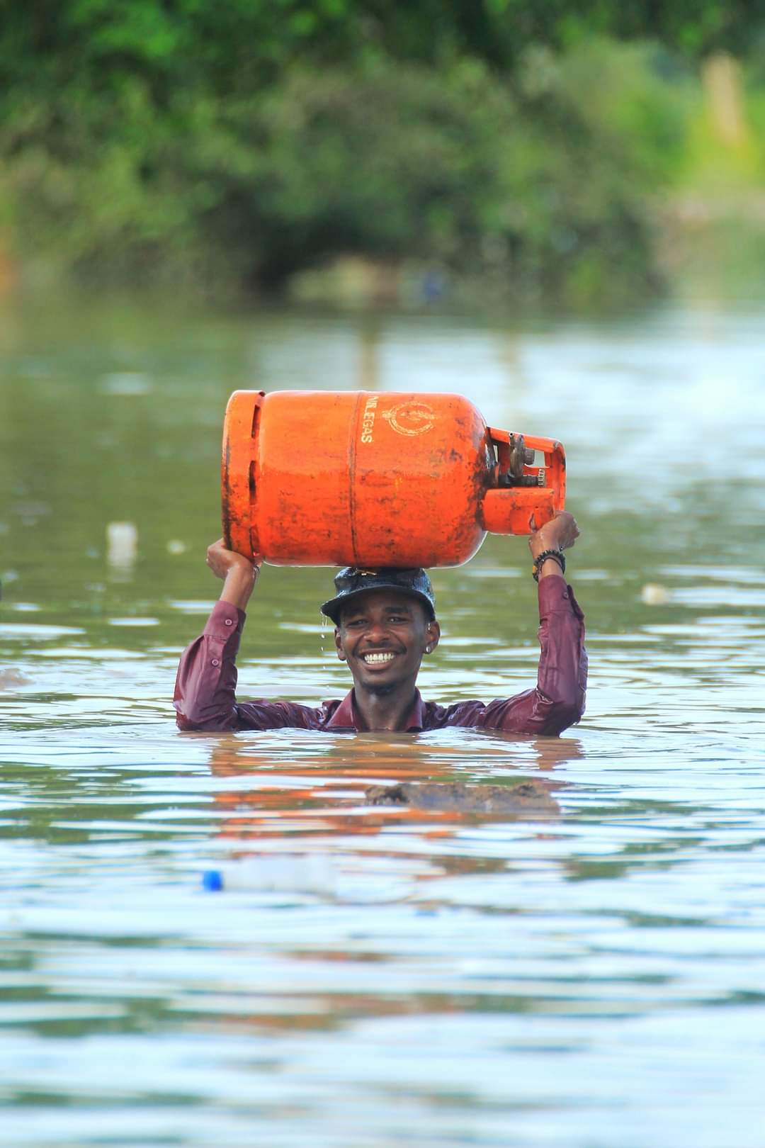 شاب يحمل أنبوبة بوتاجز وسط الفيضانات