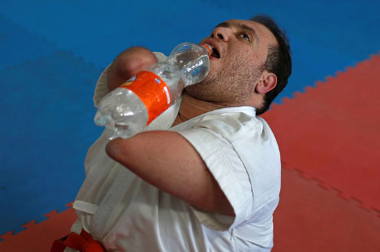 أبو عميرة يشرب الماء وهو يمارس رياضة الكاراتيه في نادٍ بغزة