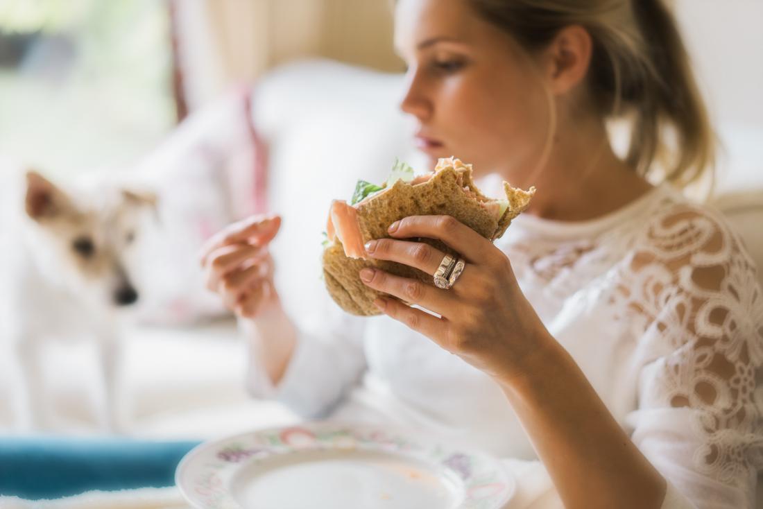 woman-experiencing-compulsive-eating-before-period-holding-a-sandwich
