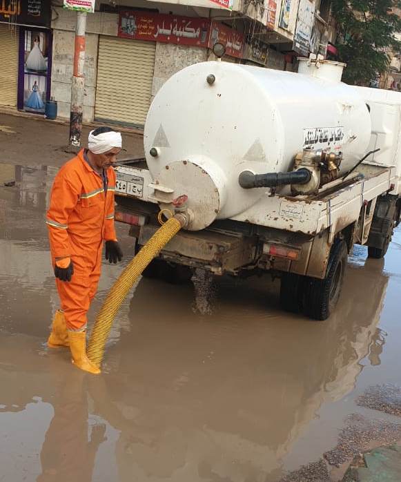 أحد العمال يشفط المياه من الشارع