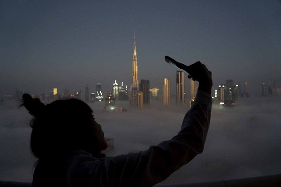 فتاة تلتقط صورة سيلفي خلال ضباب كثيف في دبي