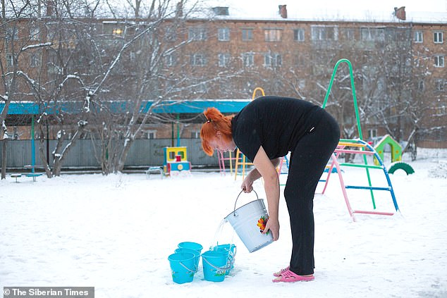 مدرس في مدرسة حكومية تملأ دلوًا من الماء البارد ليغمر الأطفال أنفسهم به في سيبيريا ، روسيا