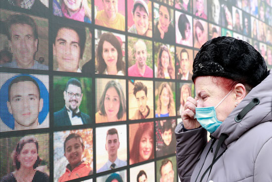سيدة تبكي أمام لوحة مجمعة لضحايا الطائرة