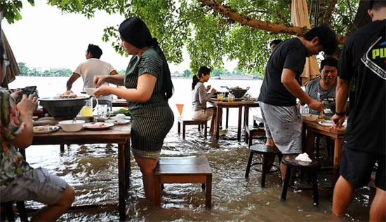 ظل مقهى Chaopraya Antique ، في Nonthaburi ، بالقرب من بانكوك ، مفتوحًا على البريد ويتدفق العملاء للاستمتاع بإثارة تجنب الأمواج الناتجة عن مرور القوارب
