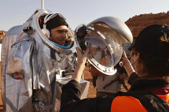 تقنيون يساعدون رواد الفضاءعلى ارتداء زي رائد فضاء، أثناء التدريب