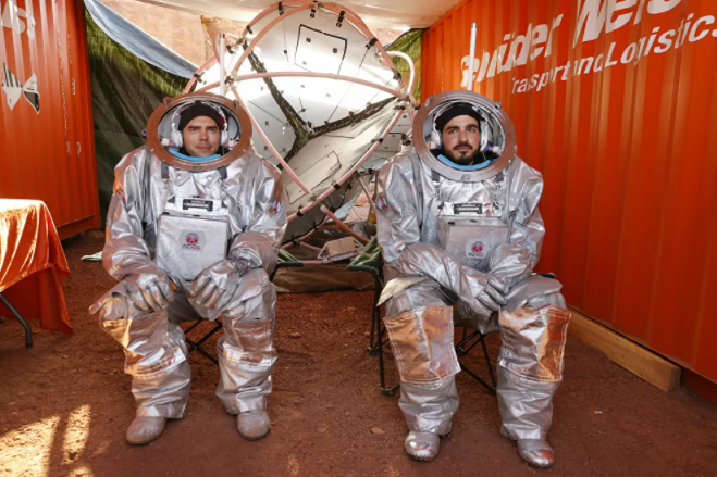 اثنان من رواد الفضاء يجلسان داخل ما يشبه قمرة المركبة الفضائية، أثناء التدريب