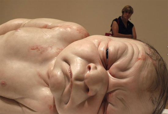 امرأة تنظر إلى منحوتة طفل للنحات الأسترالي رون مويك